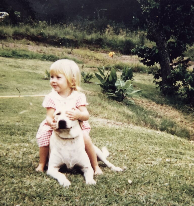 Young blonde girl sits on a labrador dog