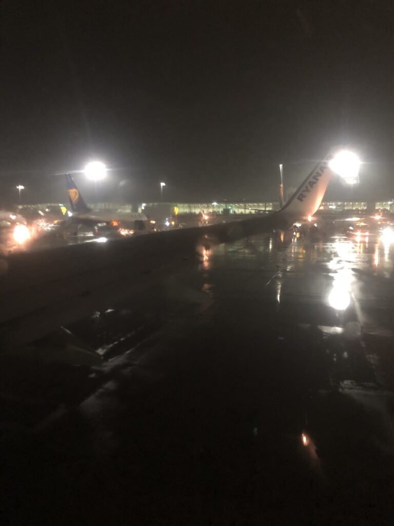 Picture taking through a window of a rainy scene of an airplane wing at an airport